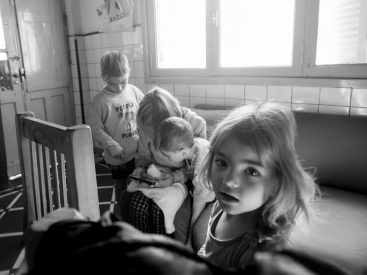 A candid black and white photo of children interacting indoors, creates a classic moment.