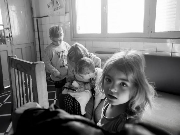 A candid black and white photo of children interacting indoors, creates a classic moment.